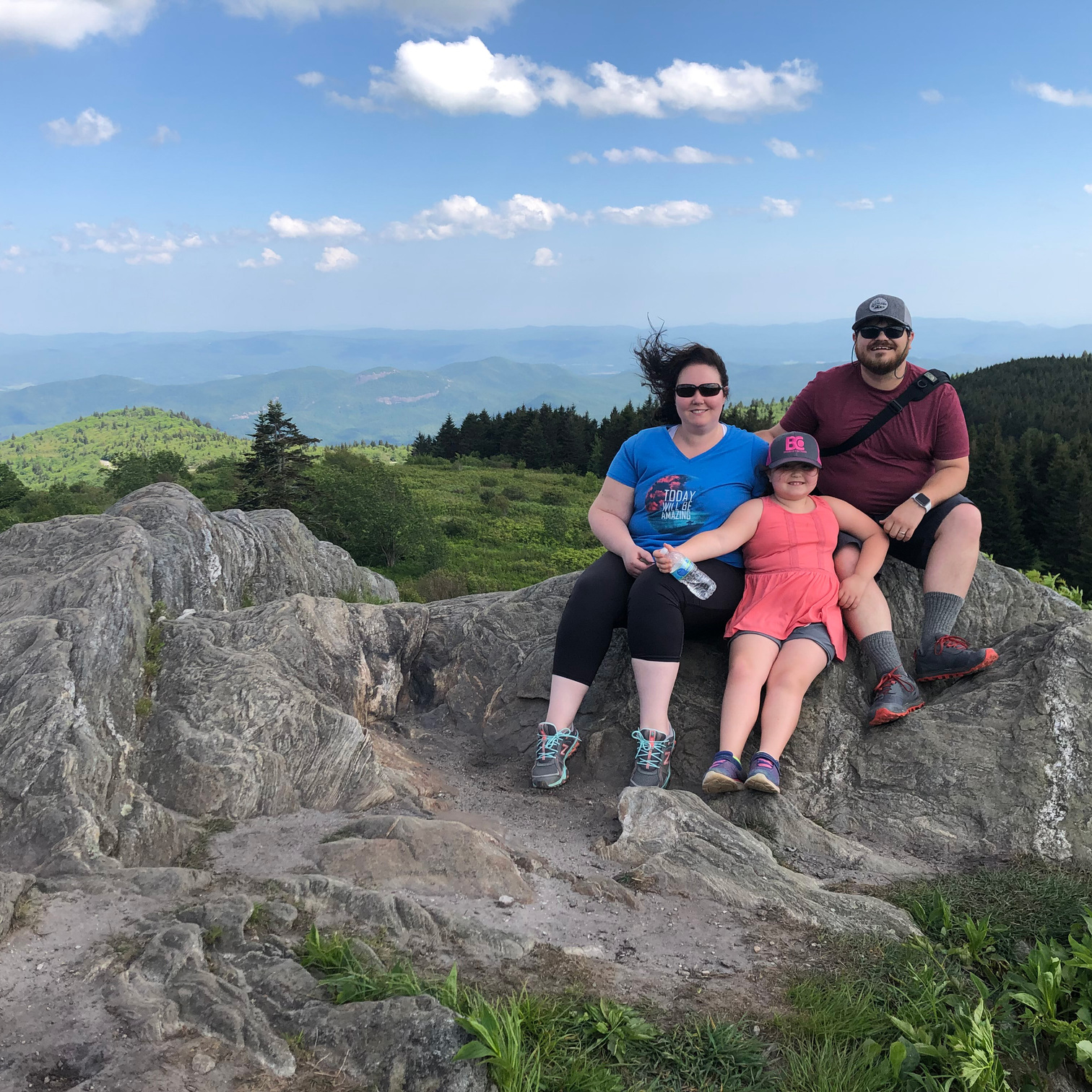 Cullen Whitmore sitting on a rock with his wife and daughter