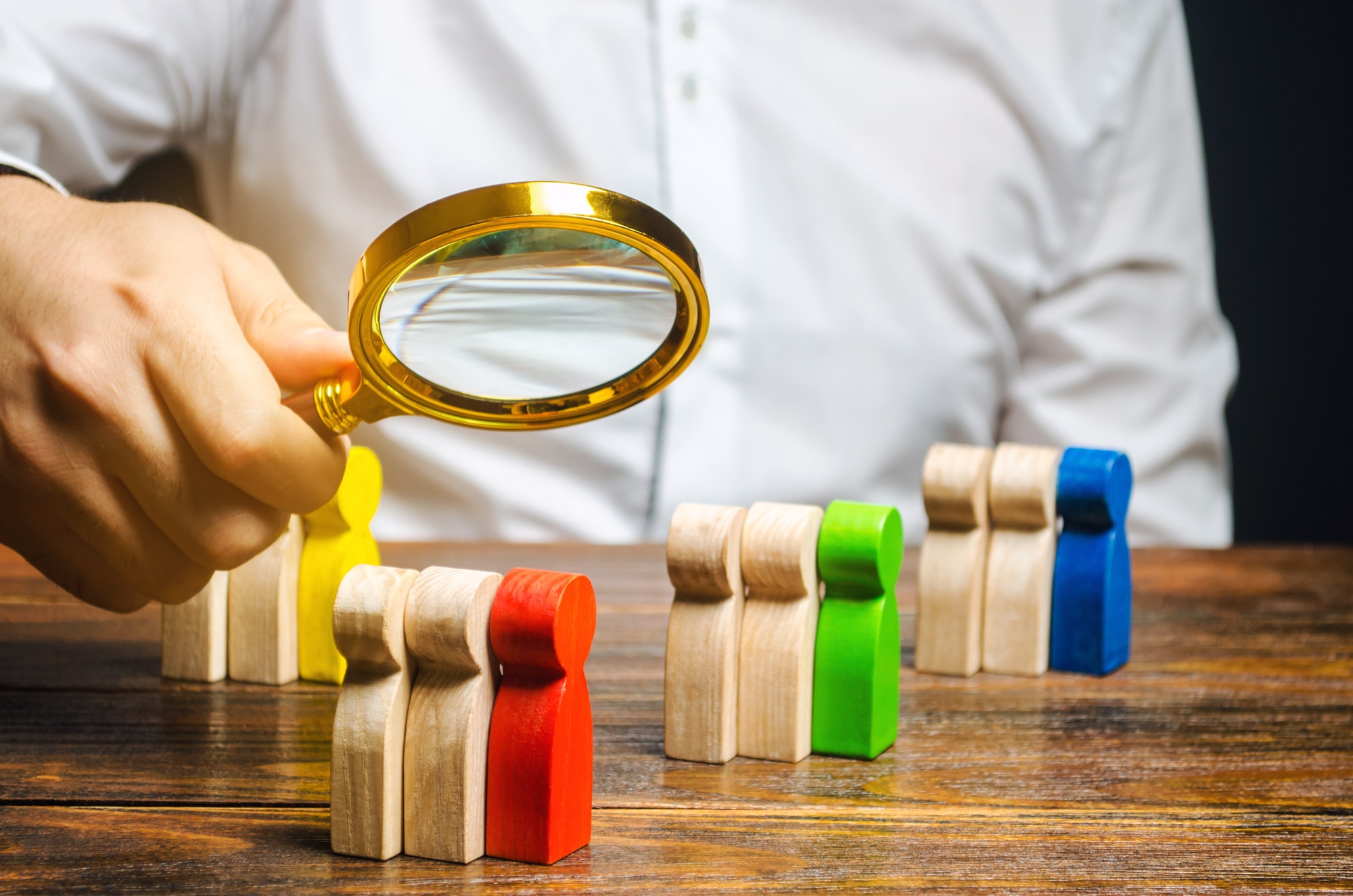 Build Target Audiences. Man with magnifying glass looking at wooden audiences.