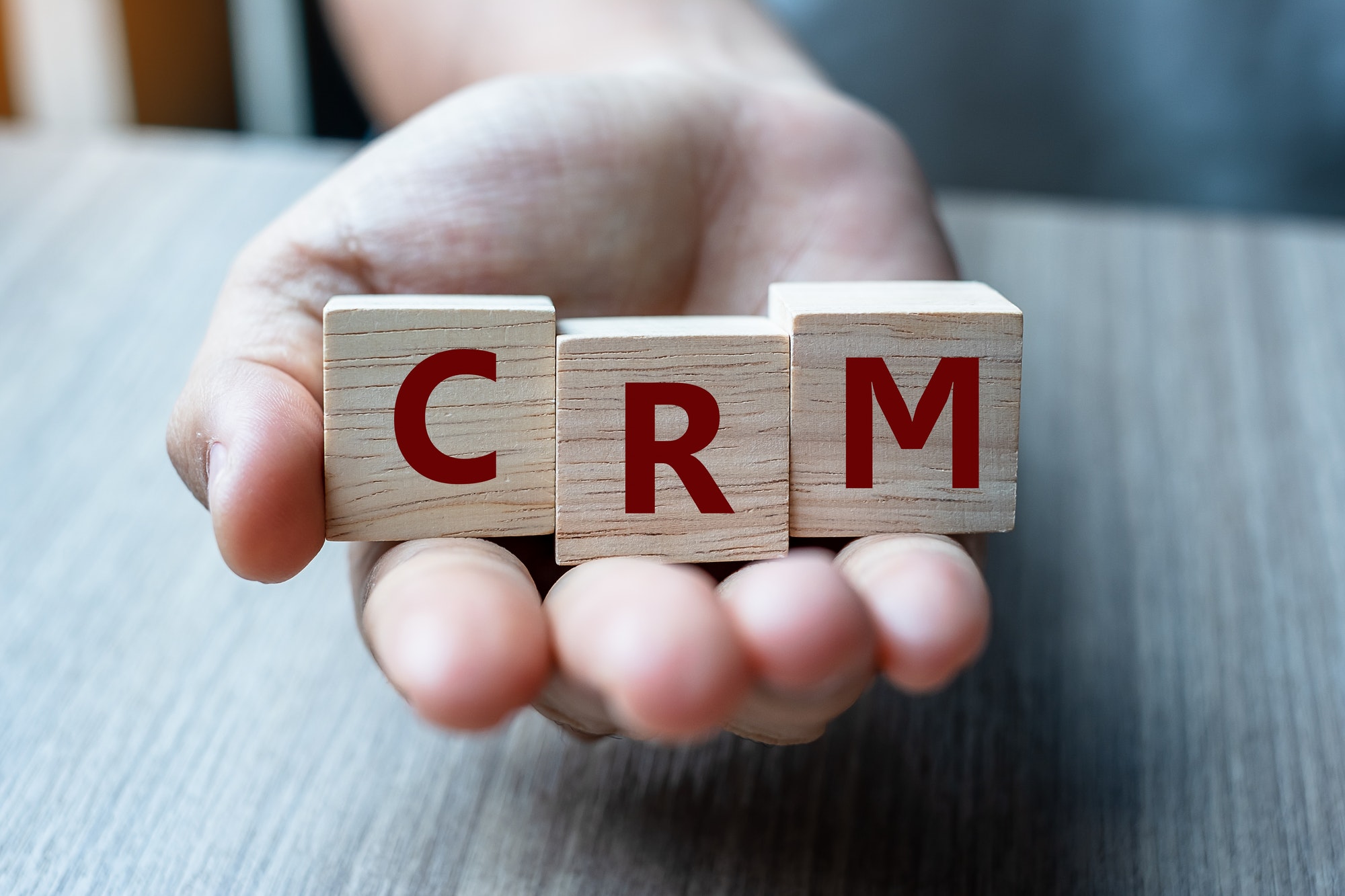 Business woman hand holding wooden cube with CRM text (Customer Relationship Management).