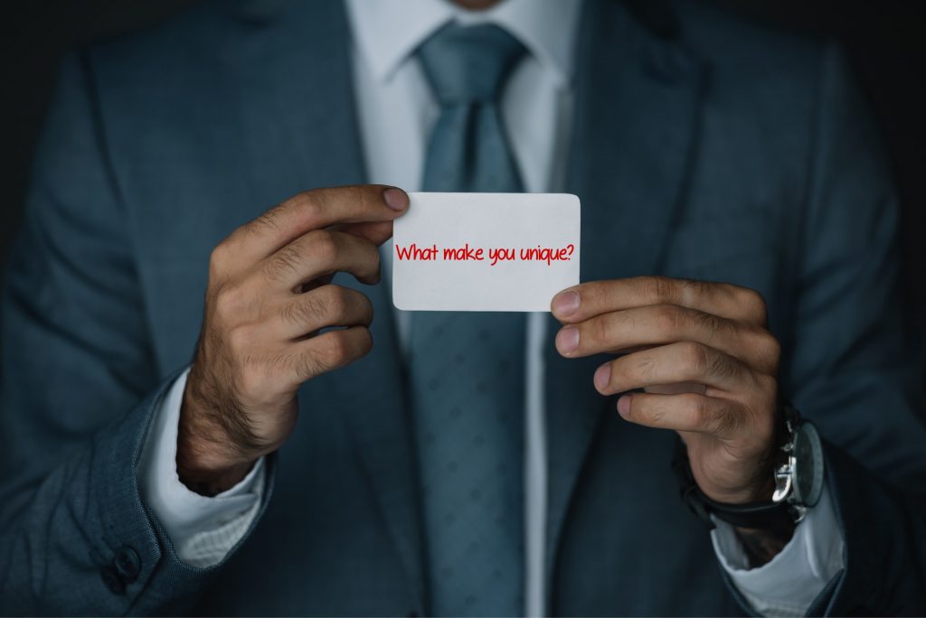 Man holding up card that says "what make you unique"?