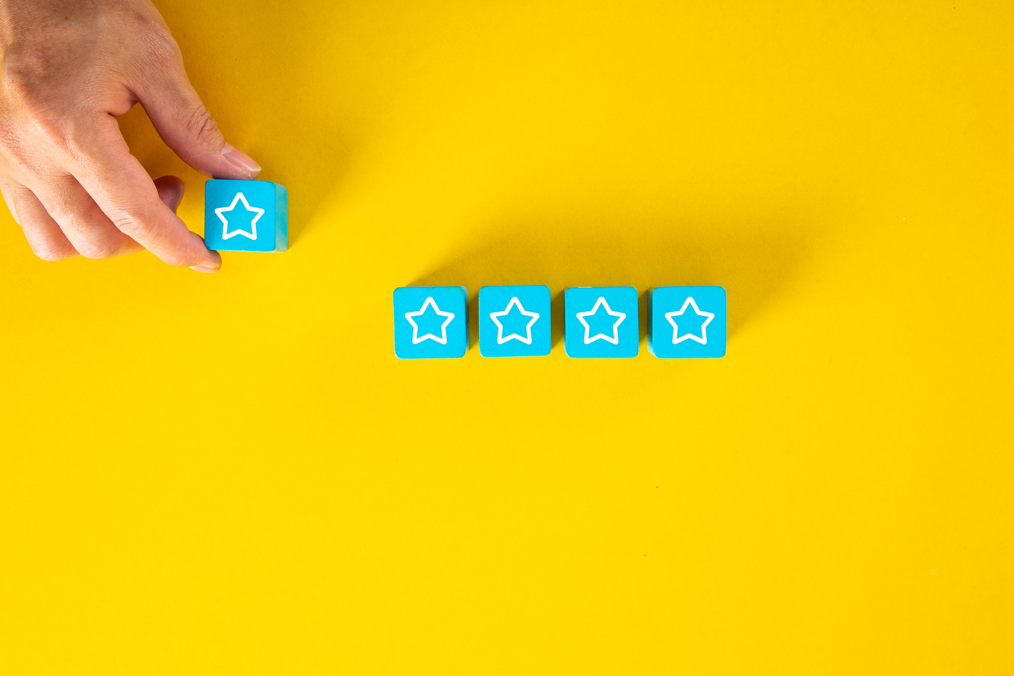 Male hand placing wooden cubes with five star rating for Clutch reviews.