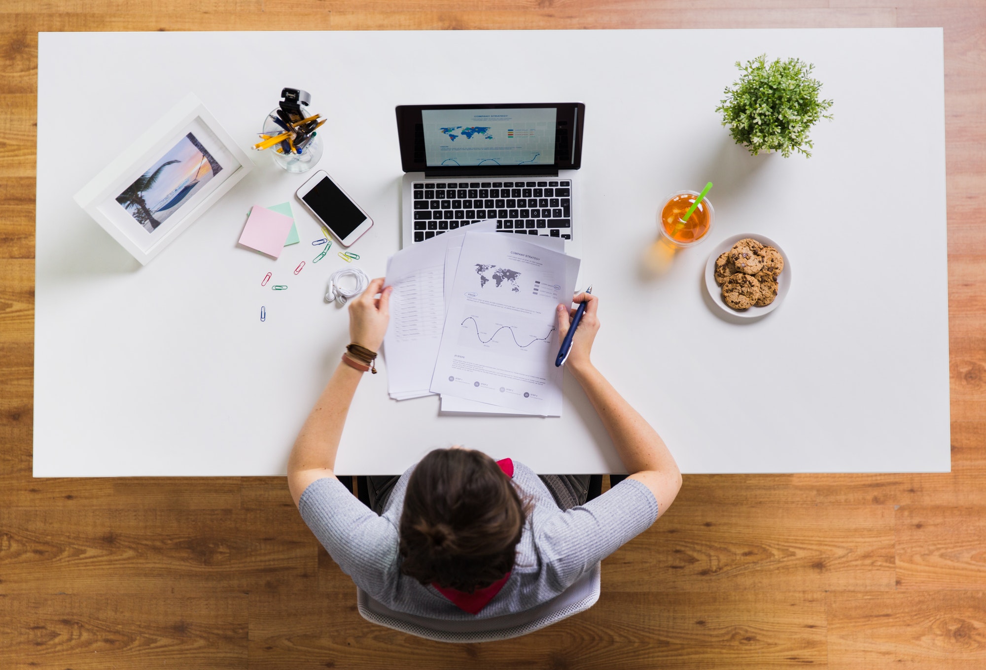 Woman with laptop and papers at office table looking at engagement Metrics