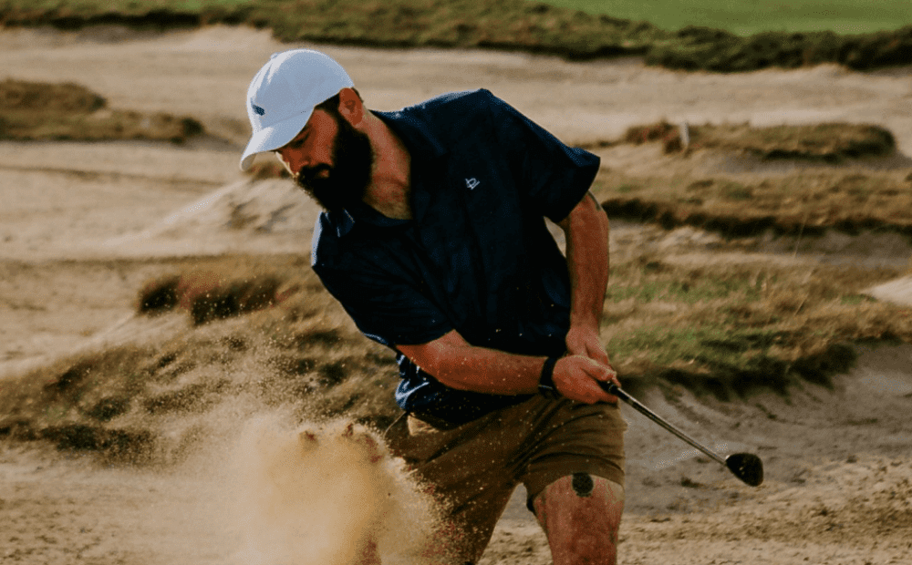 Golfer hitting out of a sandbox.