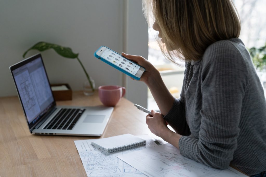 Woman designer using smartphone, takes a break from work and listens to speaker in clubhouse.