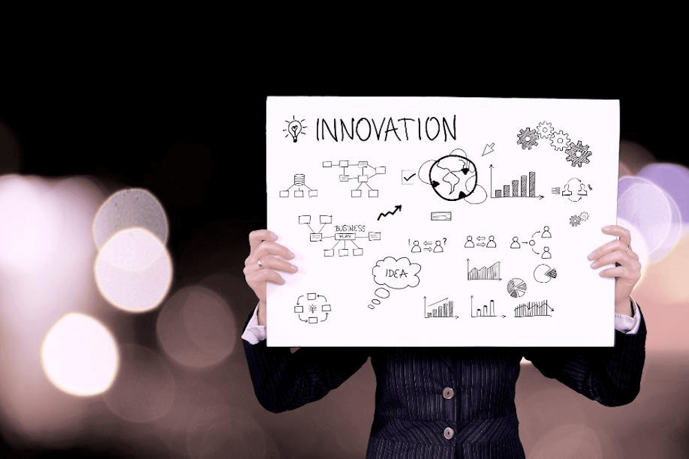 A person holding a sign that says innovation with illustrations on 